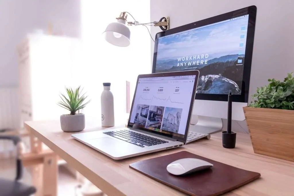 A clean, organized workspace featuring a laptop, desktop computer, and minimalist desk setup by house cleaning services in Los Angeles.